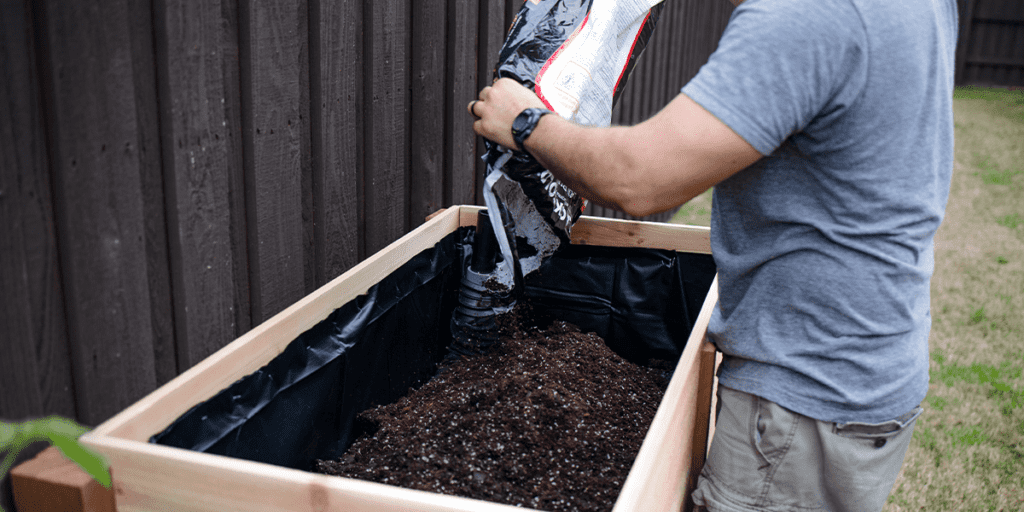 Platt Hill Nursery man putting soil into raised garden bed